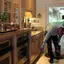 Roach control technician applying kitchen treatment along baseboards in {city}, {state}